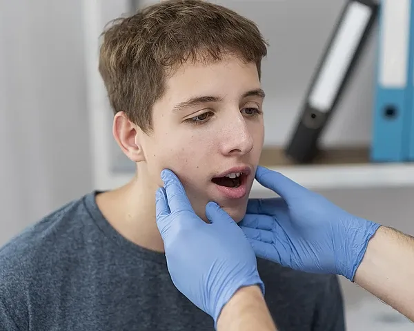 Mann wird von einer Kieferorthopädin wegen Beschwerden durch einen schmalen Oberkiefer untersucht.