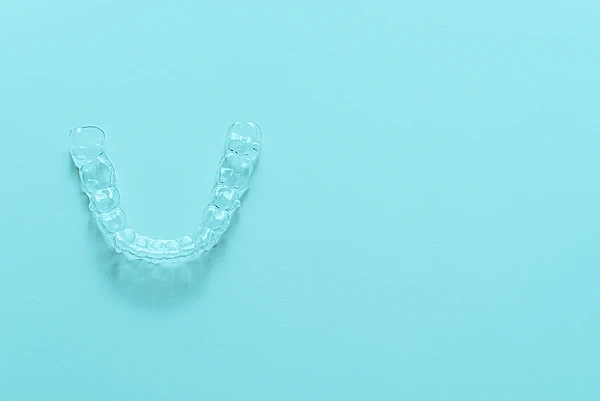 Transparente Aligner-Zahnschiene auf türkisem Hintergrund für die unauffällige Korrektur von Zahnfehlstellungen.